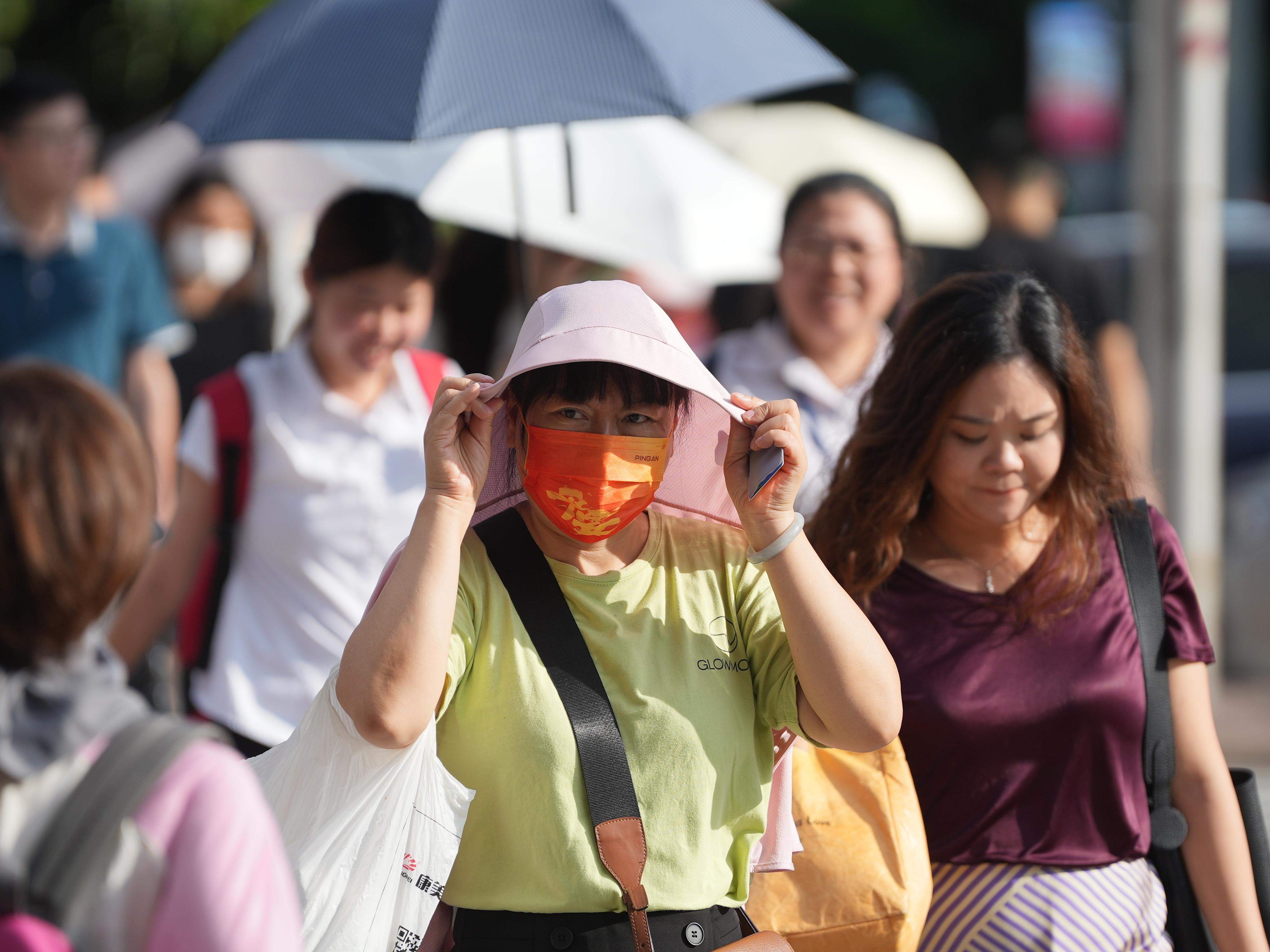 7月24日,广州继续受高温天气影响,市民用外衣遮挡阳光。羊城晚报全媒体记者 梁怿韬 摄